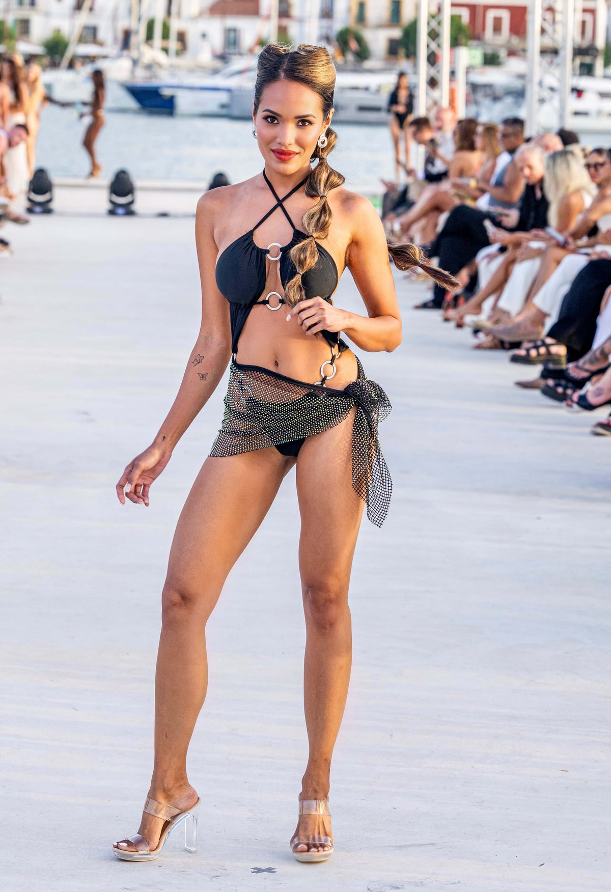 Model showcasing the Shine Bright Mini Skirt as a tie-waist piece in a stylish outdoor runway setting.