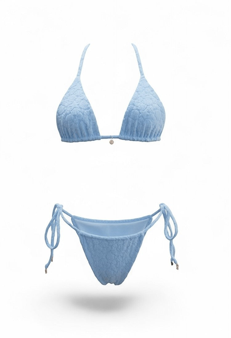 SlaySwimwear Beach Babe blue bikini with 3D shell print fabric, adjustable ties, and gold charm accents.