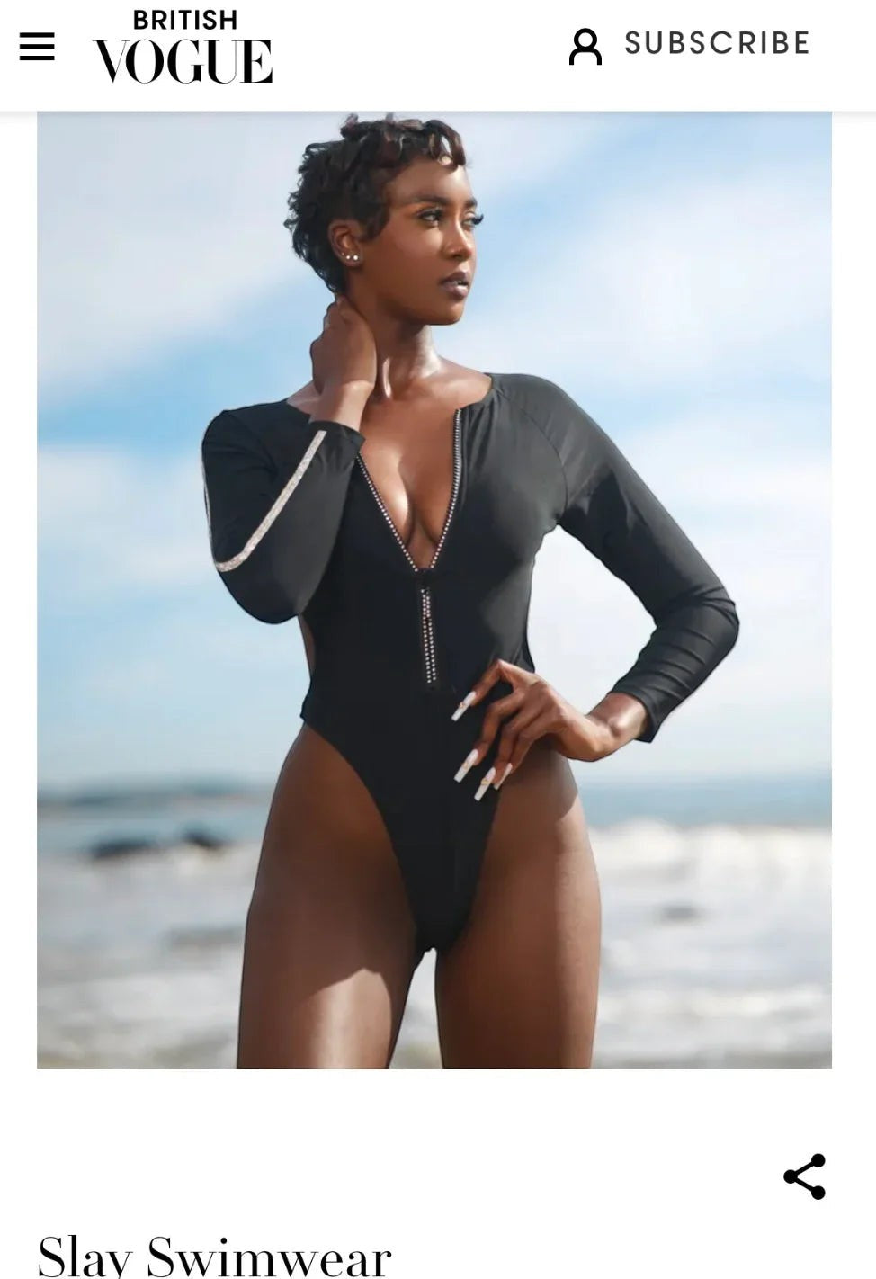 SlaySwimwear black long-sleeve one-piece swimsuit with zip front, side cutouts, and jeweled T-back hardware.
