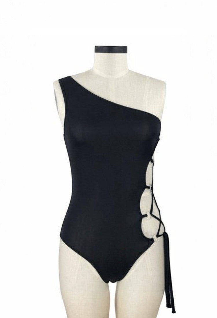 SlaySwimwear black one-shoulder swimsuit with lace-up side cutouts and adjustable ties.