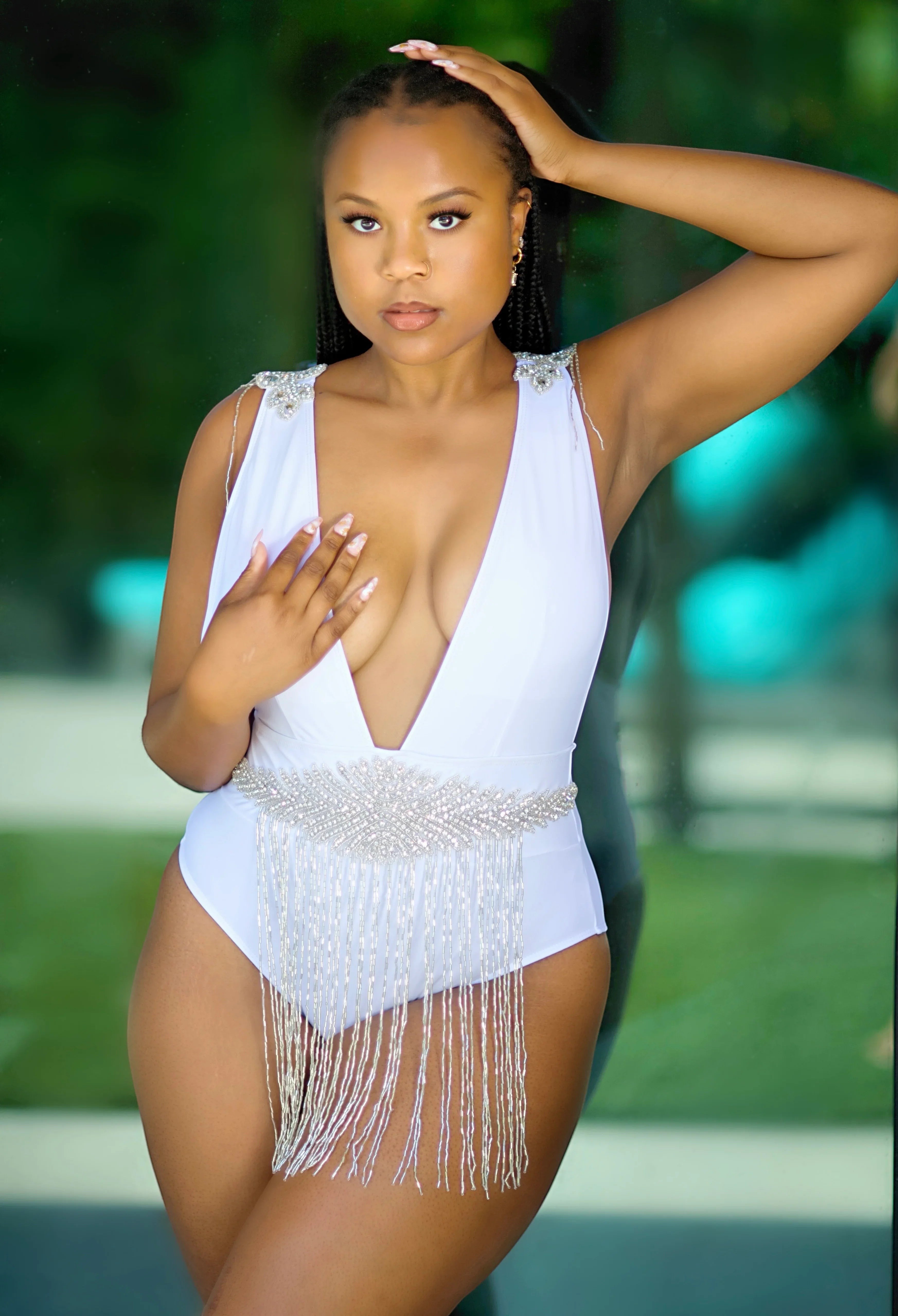 SlaySwimwear white one-piece swimsuit with plunging neckline, rhinestone embellishments on shoulders and a beaded fringe belt.