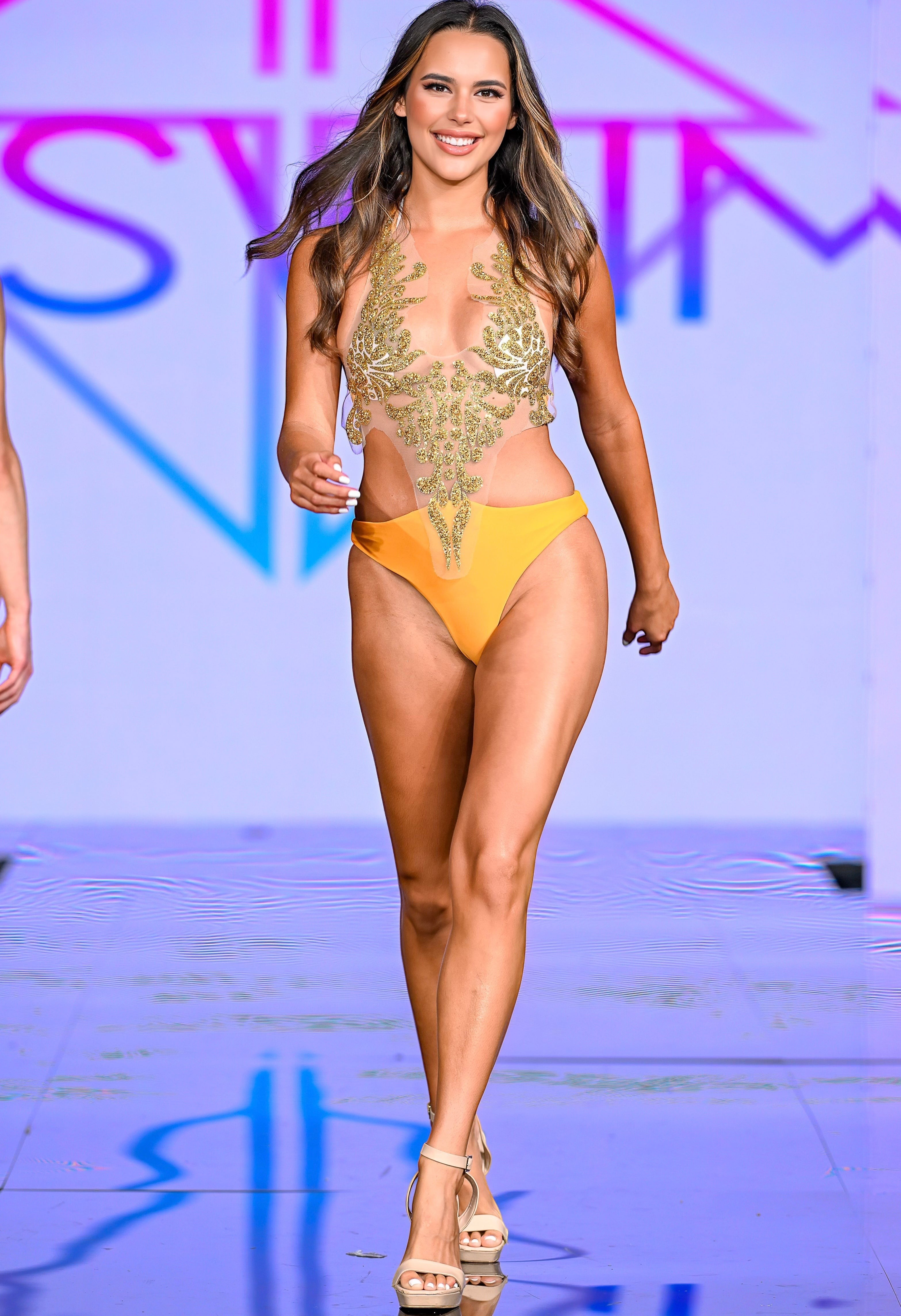 SlaySwimwear model in a yellow one-piece swimsuit with a sheer, gold-embellished bodice. Beachwear.