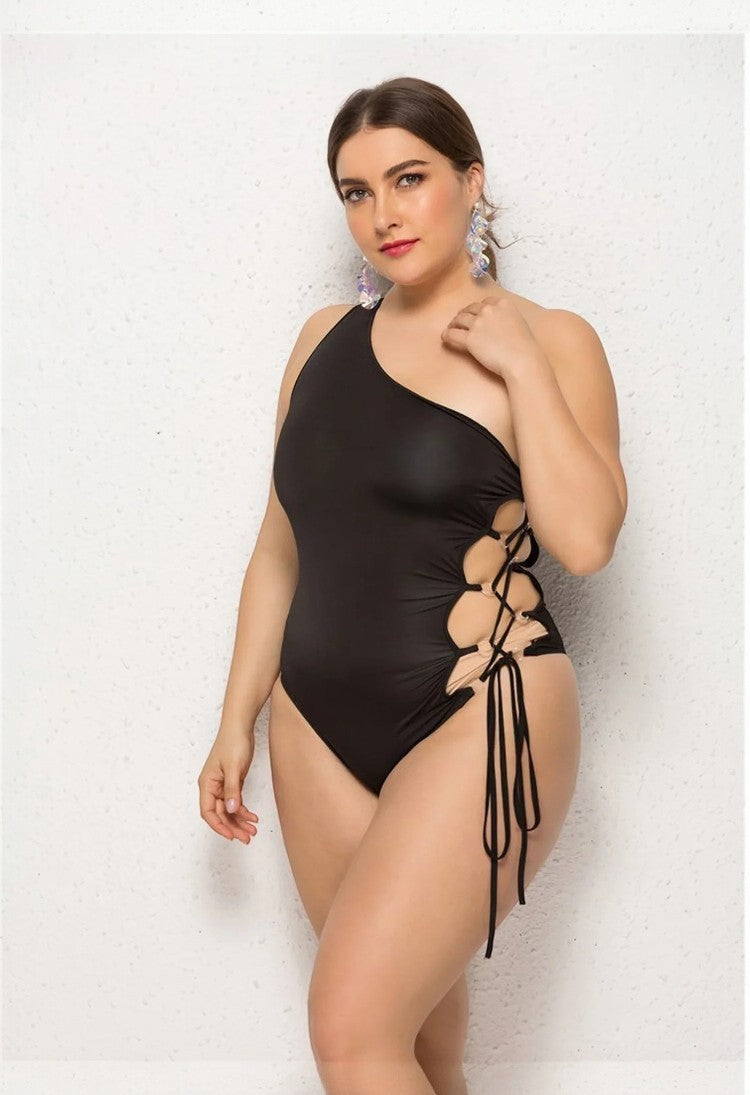 SlaySwimwear black one-shoulder lace-up swimsuit with side cutouts and adjustable ties.