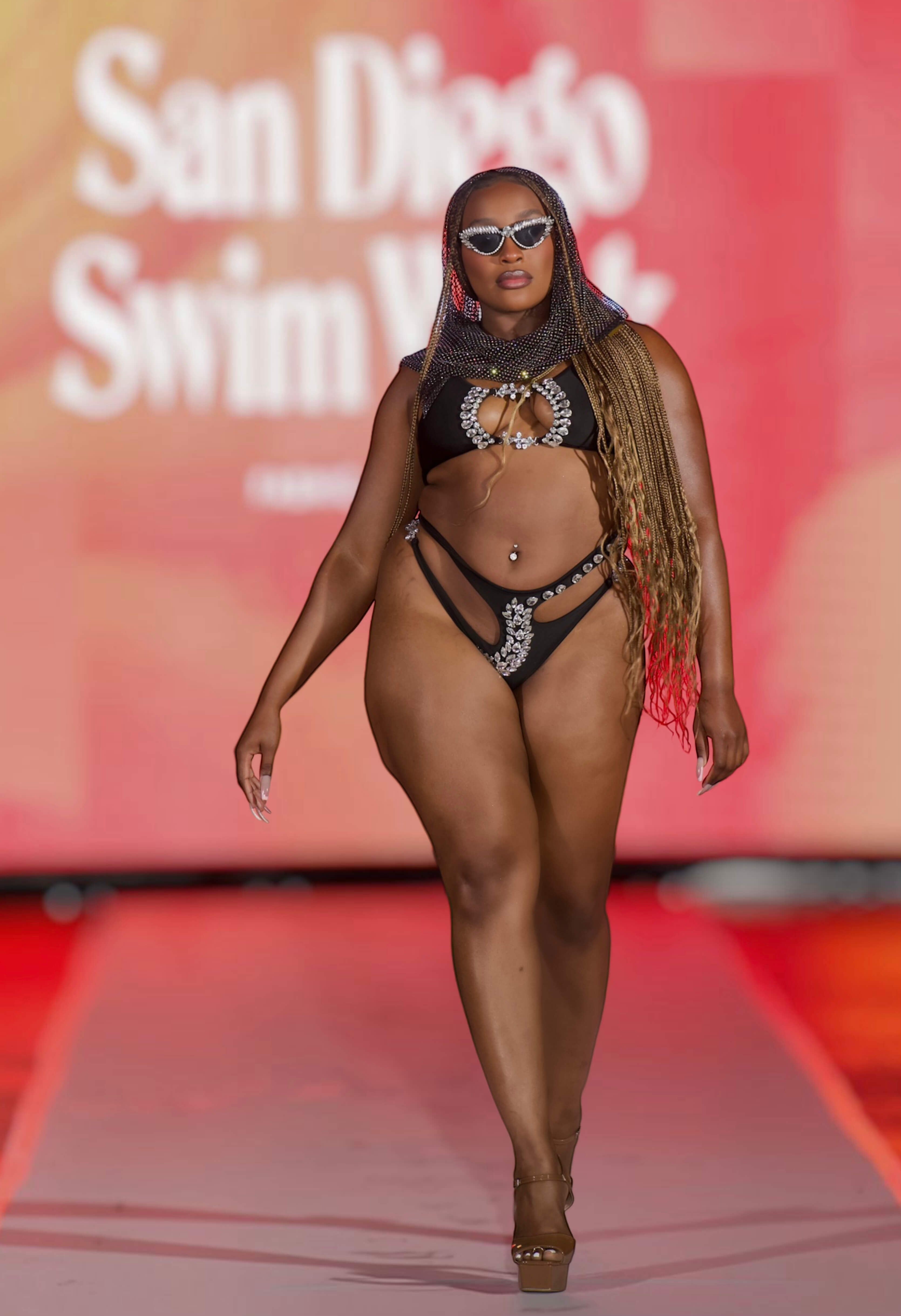 SlaySwimwear Black Beauty rhinestone bikini set with triangle top and cutout bottoms on a runway model.