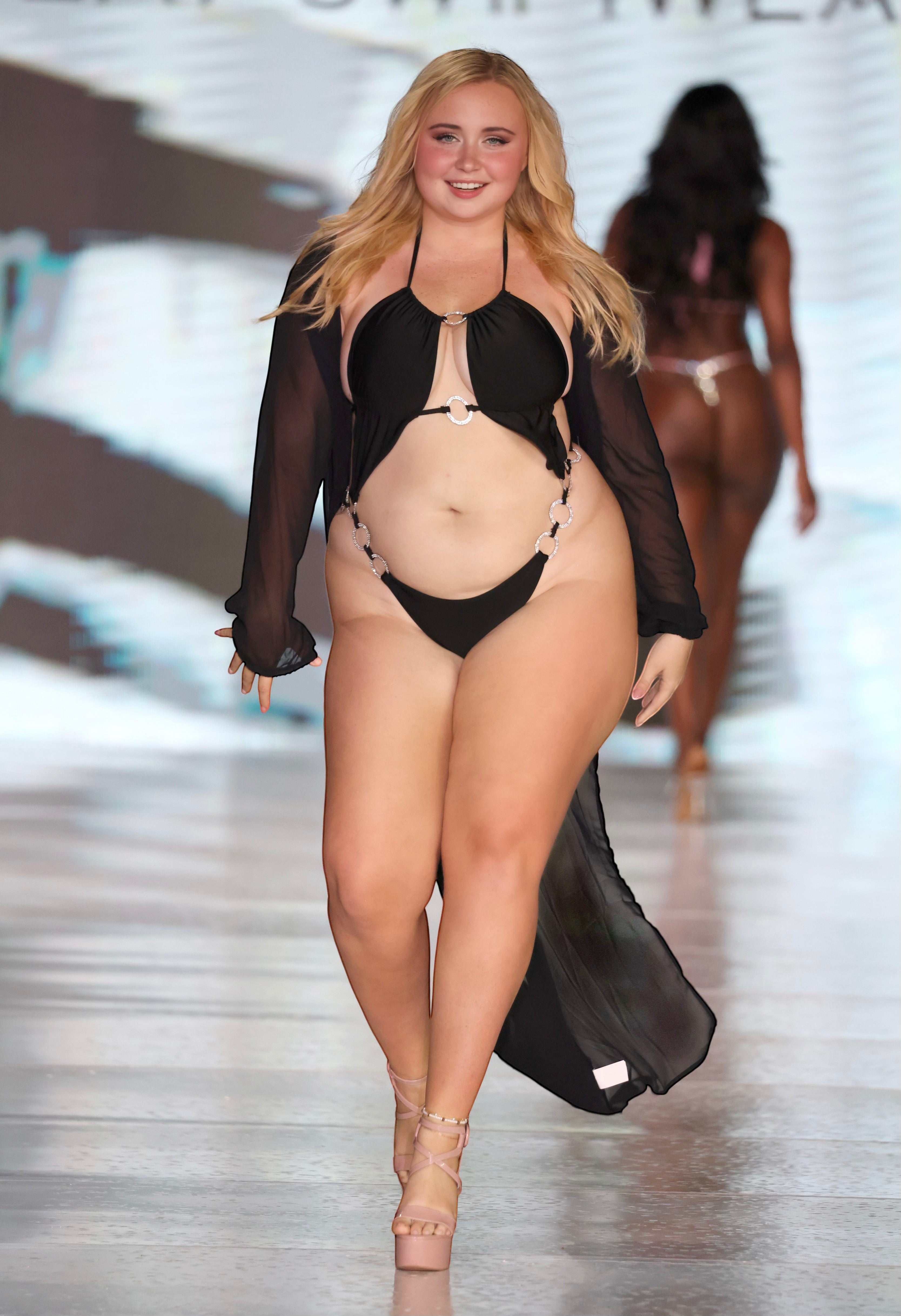 SlaySwimwear black monokini with O-ring cutouts and rhinestone accents, adjustable halter top, high-cut leg, and sheer black cover-up.