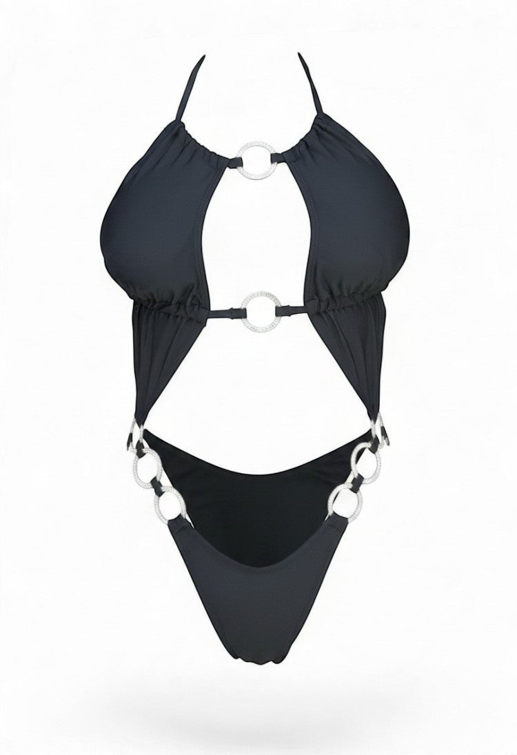 SlaySwimwear black one-piece swimsuit with plunging neckline, strappy details, and silver ring accents on bust, waist, and hips. High-cut leg.