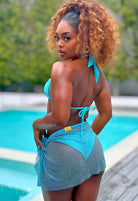 SlaySwimwear blue rhinestone mini skirt with clasp closure, worn by a model posing by a pool.