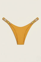 SlaySwimwear Golden Gem bikini bottoms in mustard yellow with jeweled straps on hips.