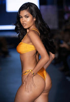 SlaySwimwear Golden Gem bikini set in shimmering yellow with jewel-embellished straps and hip details. Features a structured top and sculpted bottoms.