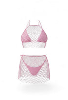 SlaySwimwear pink rhinestone fishnet halter top and mini skirt set on a woman at the beach.