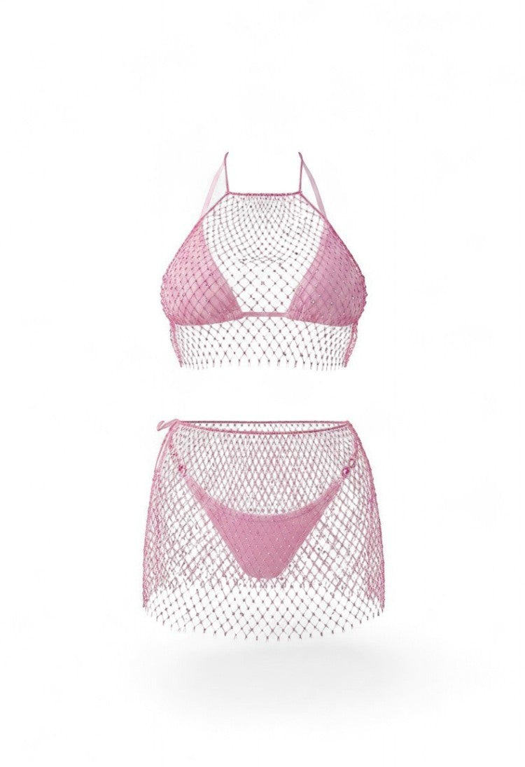 SlaySwimwear pink rhinestone fishnet halter top and mini skirt set on a woman at the beach.