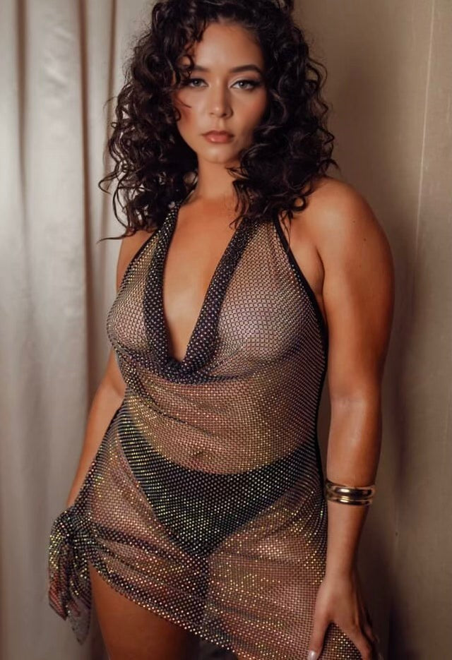 Slay Swimwear's limited edition Shine Bright Dress, a sheer rhinestone fishnet mini dress with a cowl neck and halter straps, worn as a cover-up.