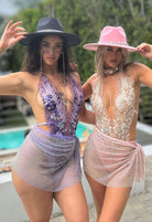 SlaySwimwear women's mini skirt with all-over sparkle, rhinestone clasp closure, and above-the-knee length. Available in purple and pink.