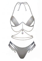 SlaySwimwear silver bikini set with rhinestone embellishments and crystal-style accents. Halter top and matching bottoms.