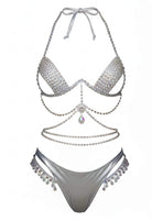 SlaySwimwear silver bikini set with rhinestone embellishments and crystal-style accents. Halter top with dangling chain detail and matching bottoms with fringe.