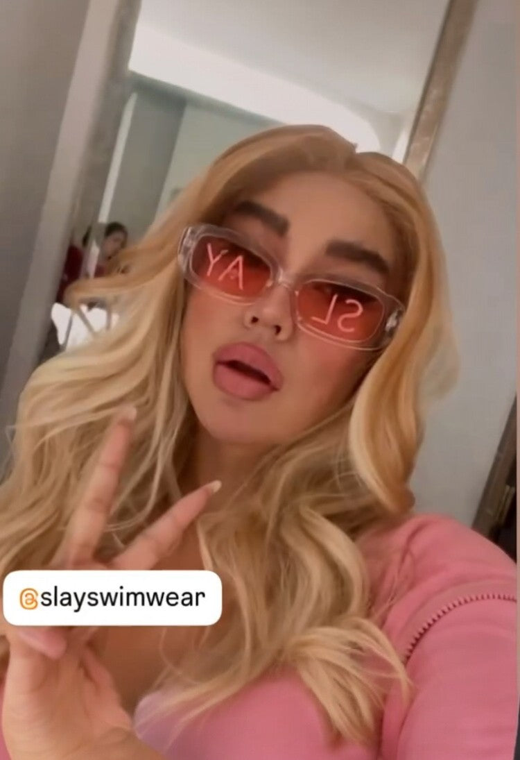 SlaySwimwear translucent pink rectangular statement sunglasses with red "SLAY" text on lenses.