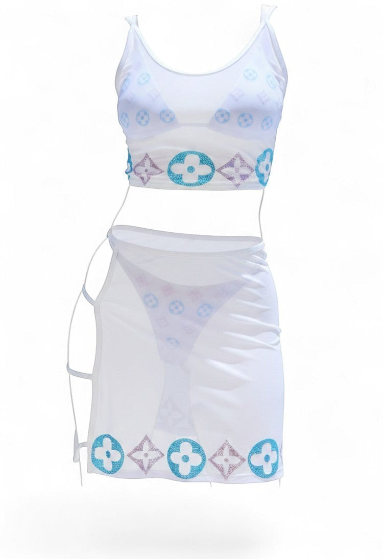 SlaySwimwear white sheer mesh crop top with rhinestone motif detailing and matching bikini bottom and sarong skirt.