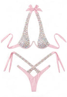SlaySwimwearHere pink bikini with all-over iridescent rhinestones, halter neck with bow detail, and high-cut cheeky bottoms.